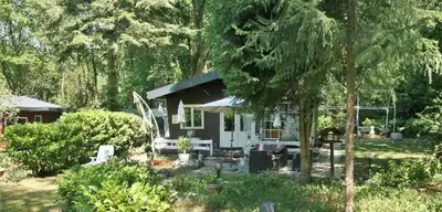 a small white house in the middle of a yard at Nieuw vebouwd Vakantie Boshuisje Meibloempje in Lanaken