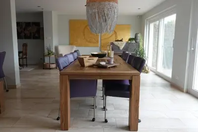 a dining room with a wooden table and purple chairs at Den 118, aan de Maas in Maasmechelen