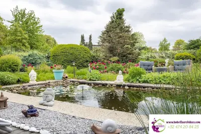 a garden with a pond with statues around it at B&b La Villa Orchidées, breakfast included in Bassenge