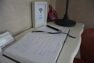 a desk with a book and a lamp and a sign at B&b La Villa Orchidées, breakfast included in Bassenge