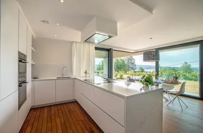 a kitchen with white cabinets and a large window at Au bois du Sart-Tilman in Sur le Mont