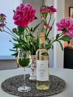 a bottle of wine next to a glass and flowers at B&B Gellick in Lanaken