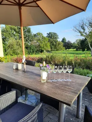 a wooden table with wine glasses and an umbrella at B&B Gellick in Lanaken