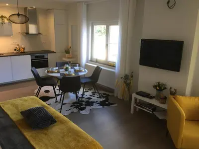 a living room with a table and a kitchen at Villa van Brienen - Studio in Dilsen-Stokkem