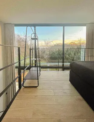 a room with a ladder in front of a large window at de Bosch in Lummen