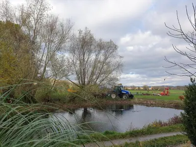a tractor is parked next to a pond at B&B La ferme du Château de Broich in Plombières