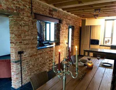 a dining room with a table and a brick wall at Huis Berenbroek in Genk