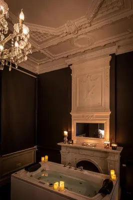 a bathroom with a tub with a fireplace and a chandelier at Maison Noppius - Love Hotel in Liège