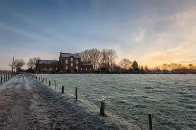 a field with a house and a fence in the snow at B&B Bloonwinning in Hasselt