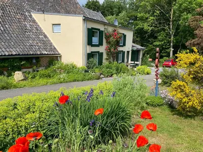 a garden in front of a house with red flowers at Bellerose Maison de Greunebennet in Plombières