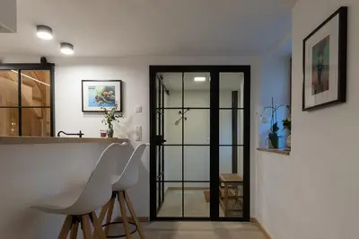 a kitchen with a counter and a door with stools at Bellerose Maison de Greunebennet in Plombières