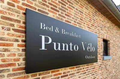 a sign on the side of a brick wall at B&B Punto Vélo in Zutendaal
