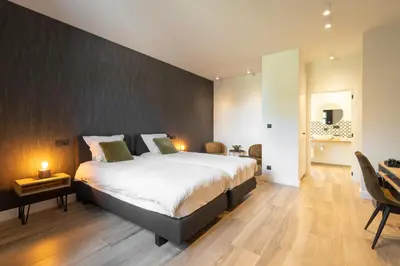 a bedroom with a large bed and a desk at B&B Punto Vélo in Zutendaal