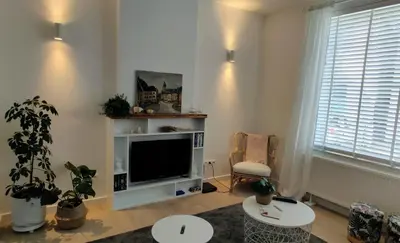 a living room with a flat screen tv and a chair at Kanne: charming house between nature and shopping in Kanne