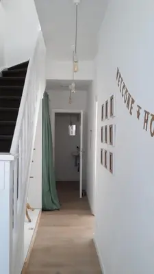 a hallway with white walls and a staircase with a green curtain at Kanne: charming house between nature and shopping in Kanne