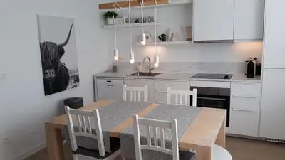 a kitchen with a table and chairs and a kitchen with white cabinets at Kanne: charming house between nature and shopping in Kanne
