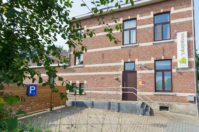 a red brick building with a brown door at Het Dorpshuys - vakantiewoning tot 12 personen in Maaseik