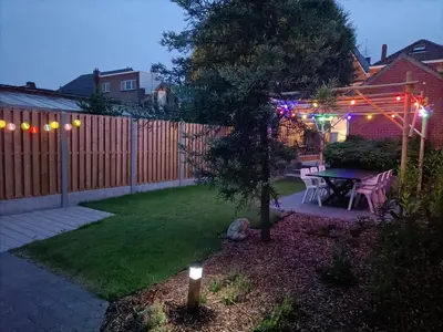 a backyard with a table and a fence with lights at Moodraz vakantiehuis centrum Peer in Peer