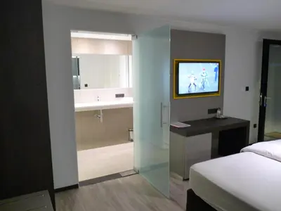 a bedroom with a bed and a bathroom with a television at Hotel Au Prince Royal in Leopoldsburg