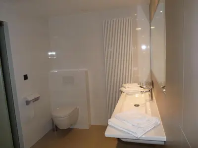 a white bathroom with a sink and a toilet at Hotel Au Prince Royal in Leopoldsburg
