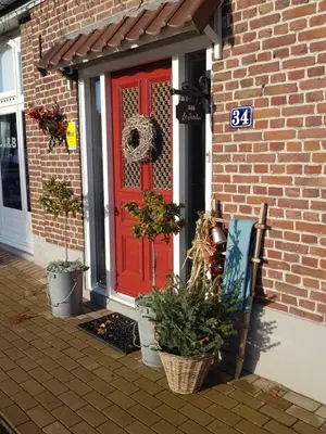 a red door on a brick house with potted plants at B&B Le Jardin in Pelt