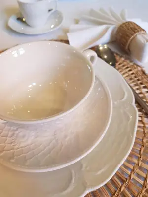 a white bowl on a plate on a table at B&B Le Jardin in Pelt