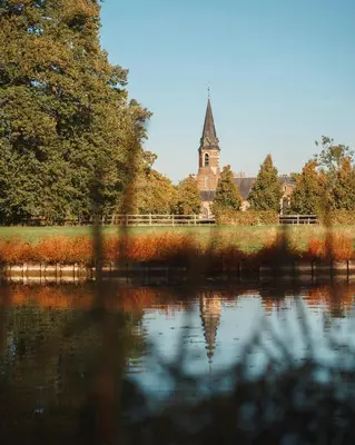 a view of a church and a lake with trees at B&B Maison Mairie Hasselt in Hasselt
