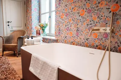 a bathroom with a white tub and floral wallpaper at B&B Maison Mairie Hasselt in Hasselt