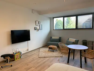 a living room with a tv and a table and chairs at Green studio-Situé à 15 min de Botrange, Parc Hautes Fa gnes et Francorchamps in Heusy