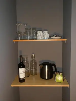 a shelf with a bottle of wine and a pot and glasses at Bosrand81 in Hechtel