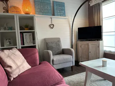 a living room with a couch and a chair and a tv at Chalet Happiness in Zutendaal