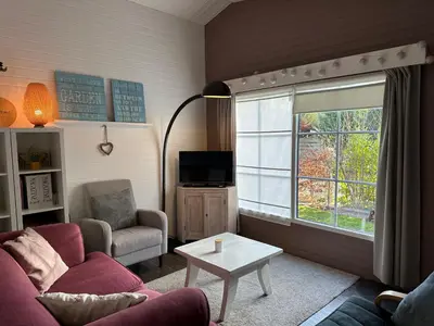 a living room with a couch and a tv and a table at Chalet Happiness in Zutendaal