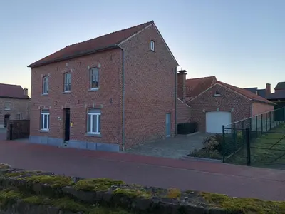 a red brick building with a white garage at Hoeve de Singel in Borgloon