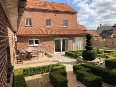 a brick house with a garden and a patio at Hoeve de Singel in Borgloon