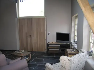 a living room with a couch and a television at B&B Hoeve Ransberg in Ransberg
