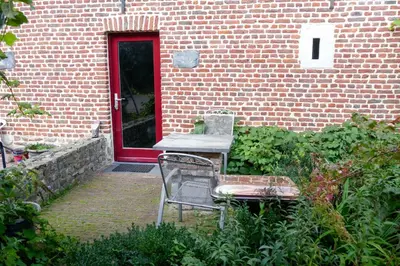 a chair and a table in front of a brick building at Apartments Cour d'Aix in Richelle