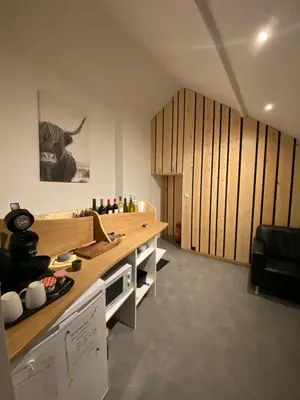 a kitchen with wooden cabinets and a cow on the wall at Une Chambre à Foyr ? in Jalhay