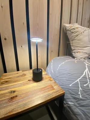 a lamp sitting on a wooden table next to a bed at Une Chambre à Foyr ? in Jalhay