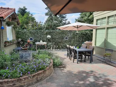 a patio with a table and chairs and an umbrella at B&B Kerkevelde in Bilzen