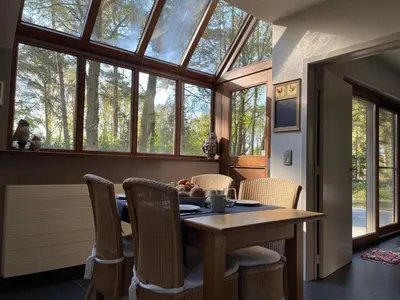a dining room with a table and chairs and windows at Sterrenheide in Heusden - Zolder