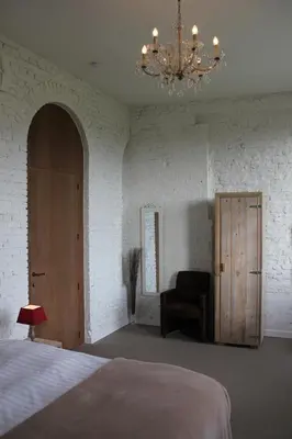 a bedroom with a bed and a chandelier and a chair at B&B Amuse-Couche in Hasselt