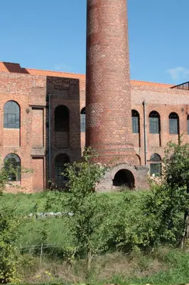 an old brick building with a tall chimney on it at B&B Amuse-Couche in Hasselt