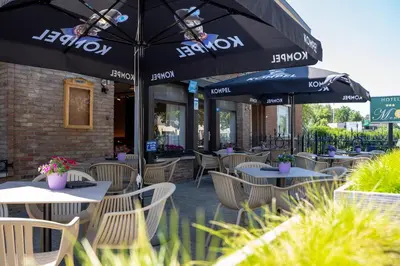 a restaurant with tables and chairs with umbrellas at Hotel Monika in Zutendaal