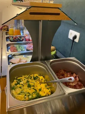a buffet line of food in a restaurant at Hotel Monika in Zutendaal