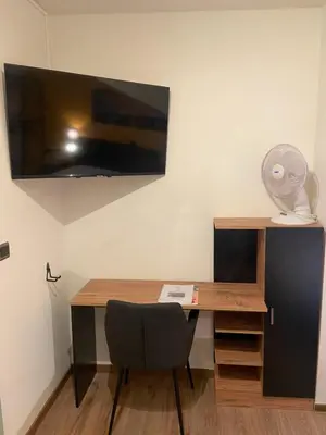 a desk with a fan and a desk with a chair at Hotel Monika in Zutendaal