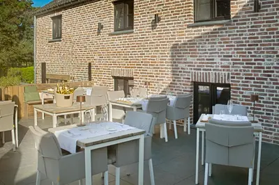 a patio with tables and chairs and a brick building at 't pure genot in Dilsen-Stokkem