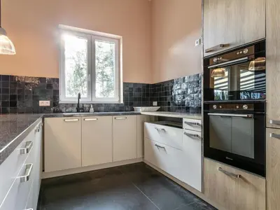 a kitchen with white cabinets and a black appliance at Ons Huis in Hechtel-Eksel
