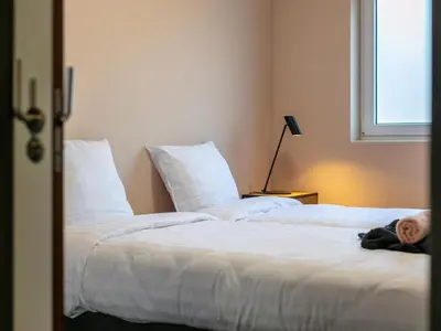 a bedroom with two beds with white sheets and a window at Ons Huis in Hechtel-Eksel