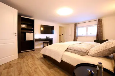 a bedroom with a bed and a desk and a television at Marias Guest House in Eynatten
