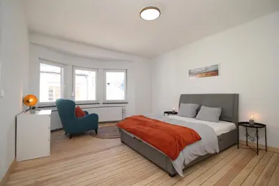 a bedroom with a bed and a blue chair at Appart Nicolas in Eupen
